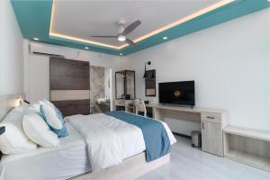 a bedroom with a bed and a desk and a television at Ukulhas Sands in Ukulhas