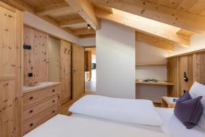 a bedroom with a white bed and wooden walls at Bäckerhof in Tesido