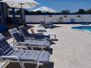 a group of chaise lounges next to a swimming pool at Monte Sol Nascente (Loft) in Grândola