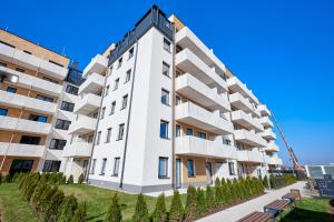 a white building with trees in front of it at Sielawy Modern Apartment by BookingHost in Poznań