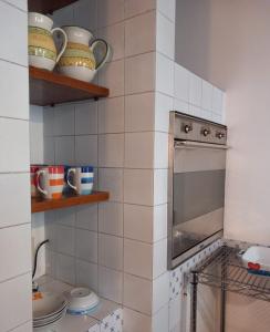 W kuchni z białymi ścianami wyłożonymi kafelkami znajduje się piekarnik. w obiekcie Radici - La finestra sui Sassi w mieście Matera