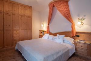 - une chambre avec un grand lit et un rideau orange dans l'établissement Hotel Castel Pietra, à Fiera di Primiero