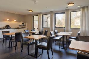 a restaurant with tables and chairs and windows at Hunzego Hotel in Uithuizermeeden