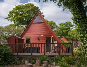 a red house with a porch and a deck at Chalet Thirteen in Deal