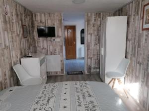a bedroom with a bed and two chairs and a television at A nyugalom szigete Tabán Apartman in Dunakeszi