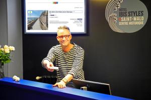 a man sitting at a desk holding a wii remote at ibis Styles Saint Malo Centre Historique in Saint Malo