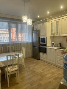 a kitchen with white cabinets and a table and a refrigerator at Квартира in Pavlodar