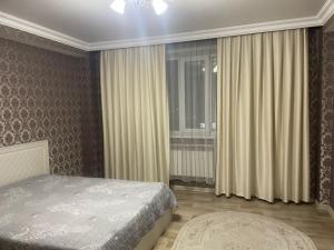 a bedroom with a bed and a window with curtains at Квартира in Pavlodar