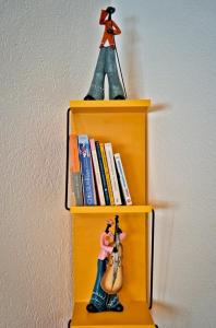 een gele plank met boeken en een beeldje van een gitaar bij Studio 5 places à deux pas du Lac in Territet