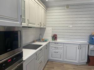a kitchen with white cabinets and a sink at Квартира in Pavlodar
