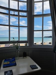 a room with three windows with a view of the beach at Lyndale Guest House in Weymouth