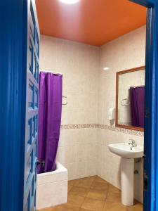 a bathroom with a purple shower curtain and a sink at Arc House Mezquita - Only adults in Córdoba