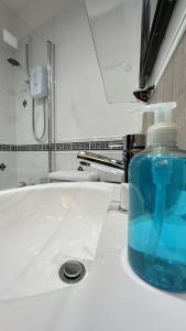 a blue bottle of soap sitting on a bathroom sink at The Pottery by Pureserviced in Plymouth