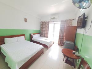 een slaapkamer met 2 bedden, een tafel en een televisie bij Khách sạn Anh Thư in Ho Chi Minh-stad