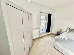 um quarto branco com uma cama e uma janela em Cozy Home Afan Valley Mountain Retreat - Sleeps -8 em Glyncorrwg