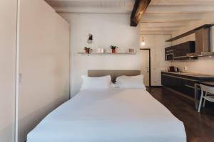 a bedroom with a large white bed and a kitchen at Charming Milan Apartments Brera - Madonnina in Milan