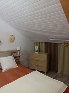 ein Schlafzimmer mit einem weißen Bett und einer Holzkommode in der Unterkunft Gîte Le clos des boucs in Les Mages