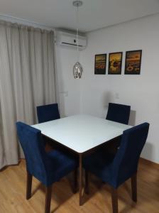 a white table and blue chairs in a room at Apartamento Cantinho do Aconchego-Nova Petrópolis in Nova Petrópolis