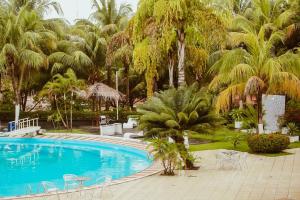 una piscina con sillas, mesas y palmeras en Barrudada Santarém, en Santarém