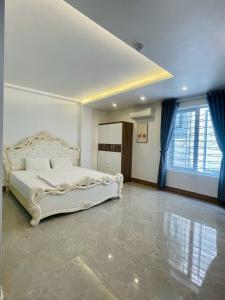 1 dormitorio con cama blanca y cortinas azules en IVY Homestay en Hai Phong