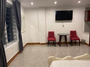 a room with two red chairs and a table and a tv at IVY Homestay in Hai Phong