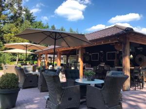 un patio con tavoli, sedie e ombrellone di Hotel De Werelt Garderen a Garderen