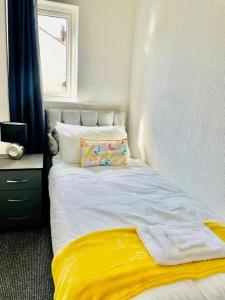 a bedroom with a white bed with a yellow blanket at Cosy 1 Bed Budget Apartment Near Blackpool City Centre 1 in Blackpool