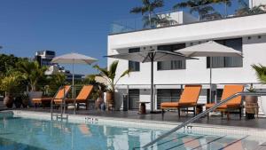um grupo de cadeiras e guarda-sóis ao lado de uma piscina em Uma House by Yurbban South Beach em Miami Beach