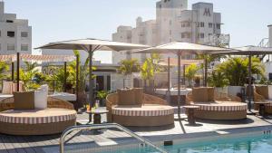 a patio with tables and umbrellas and a swimming pool at Uma House by Yurbban South Beach in Miami Beach