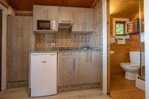a kitchen with a white refrigerator and a toilet at Camping Ria de Arosa 1 in A Pobra do Caramiñal