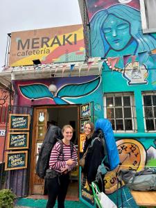deux femmes debout devant un magasin dans l'établissement Meraki Hostel - Cerro Alegre - Valparaíso, à Valparaíso