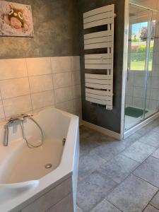 uma casa de banho com uma banheira e um chuveiro em vidro. em Hôtel Bien Être La Palmeraie em Bénouville