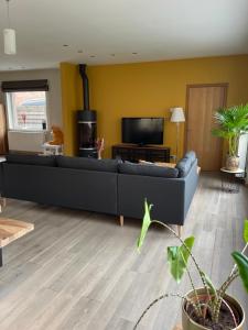 a living room with a black couch and a tv at Grote vakantiewoning nabij Brugge! in Damme