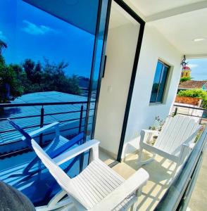 Duas cadeiras brancas numa varanda com vista para a água em Hermoso apartamento céntrico em Santa Cruz de Mompox