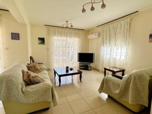 ein Wohnzimmer mit einem Sofa und einem TV in der Unterkunft Cheerful 3 bdr villa near the beach in Coral Bay