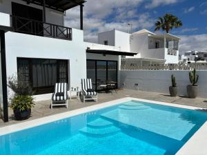 a villa with a swimming pool in front of a house at Casa Natalia in Tías