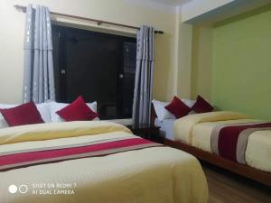 a bedroom with two beds with red pillows at Hotel Garangja in Bandipur