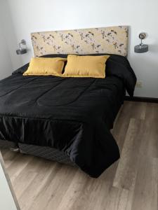 een bed met een zwart dekbed en gele kussens bij Finca La Escondida San Rafael in San Rafael