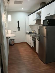 a kitchen with a stainless steel refrigerator and a wooden floor at Bungalow Esperanza in Costa Teguise +9 photos