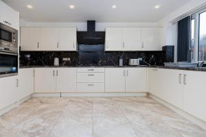 uma cozinha branca com armários e electrodomésticos brancos em Entire 4 bed new build detached house in Yorkshire em Batley Carr