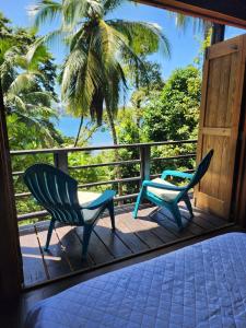 duas cadeiras num alpendre com uma palmeira em Colinas del Palmar em Bocas del Toro