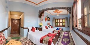 Cette chambre comprend 2 lits et une fenêtre. dans l'établissement Kasbah La Famille Berbère, à Boumalne