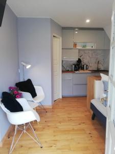 a living room with two white chairs and a kitchen at Tæt på Langesø in Morud