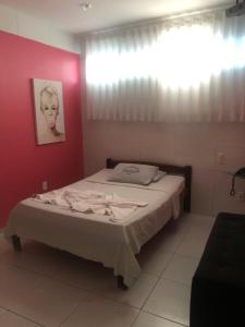 a bed in a room with a red wall at Pousada Ybyrápuan in Campina Grande