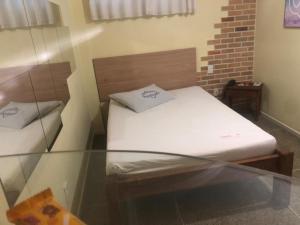 a small bed in a room with a glass table at Pousada Ybyrápuan in Campina Grande