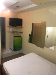 a room with a bed and a flat screen tv at Pousada Ybyrápuan in Campina Grande