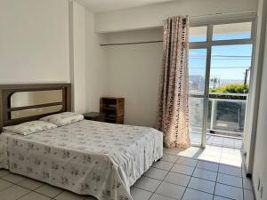 um quarto com uma cama e uma grande janela em Vista Mar na Av. principal de Jacaraípe em Serra