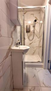 y baño blanco con lavabo y ducha. en Brand New Flat Close To Turnpike Lane Tube Station en Londres