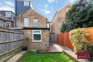 a brick house with a wooden fence in a yard at 3 Bed Victorian House - Kingston On Thames in Kingston upon Thames