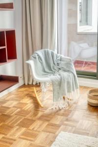 ein weißer Stuhl mit einer Decke auf einem Zimmer in der Unterkunft Cozy Retreat in Antwerp with balcony in Antwerpen